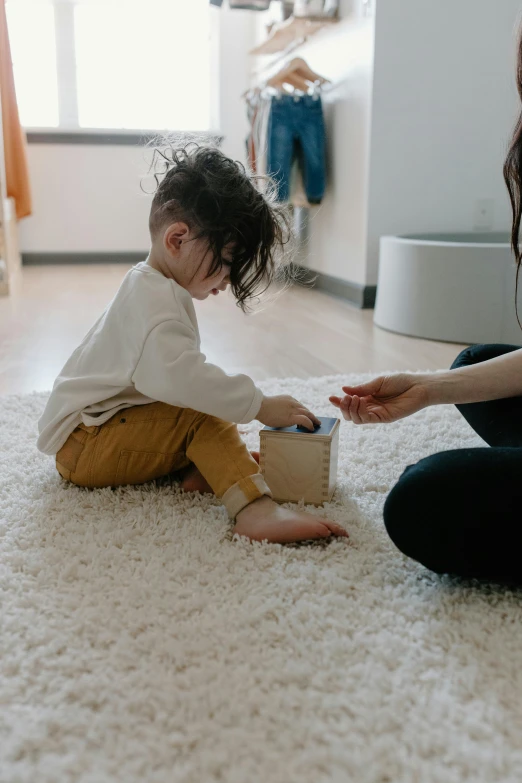 a woman sitting on the floor playing with a small child, anxiety environment, box, vomit, soft shapes