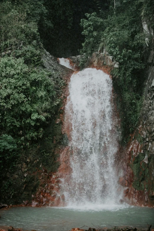 a waterfall in the middle of a lush green forest, an album cover, trending on unsplash, renaissance, faded red colors, puerto rico, high angle view, poor quality