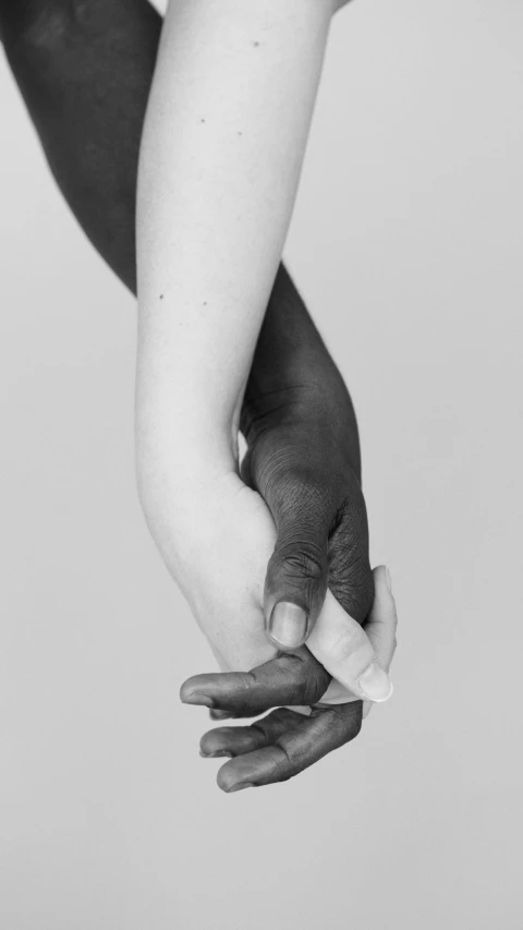 a black and white photo of a couple holding hands, by Robert Mapplethorpe, photorealism, black main color, embraced, colorless, innocence