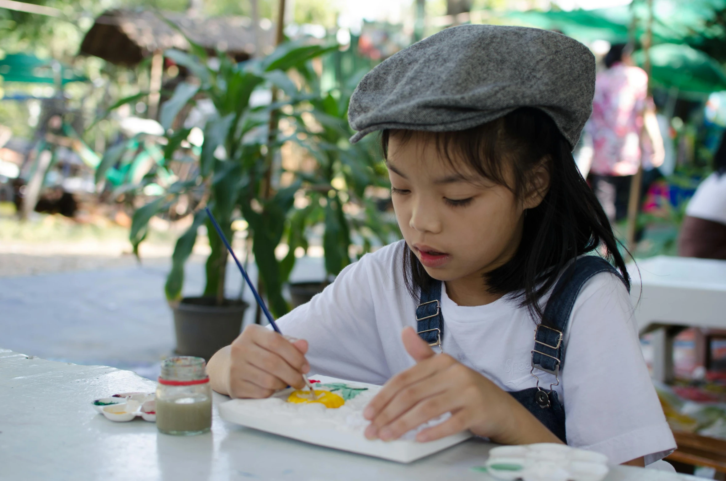 a little girl sitting at a table painting, inspired by Ruth Jên, pexels contest winner, at a park, vietnamese woman, wearing a french beret, avatar image