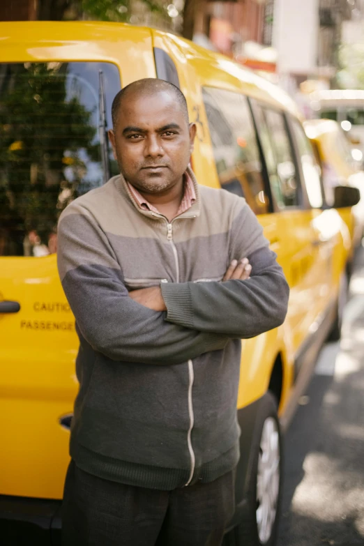 a man standing in front of a yellow taxi, he is wearing a brown sweater, jayison devadas, taken in the late 2010s, van