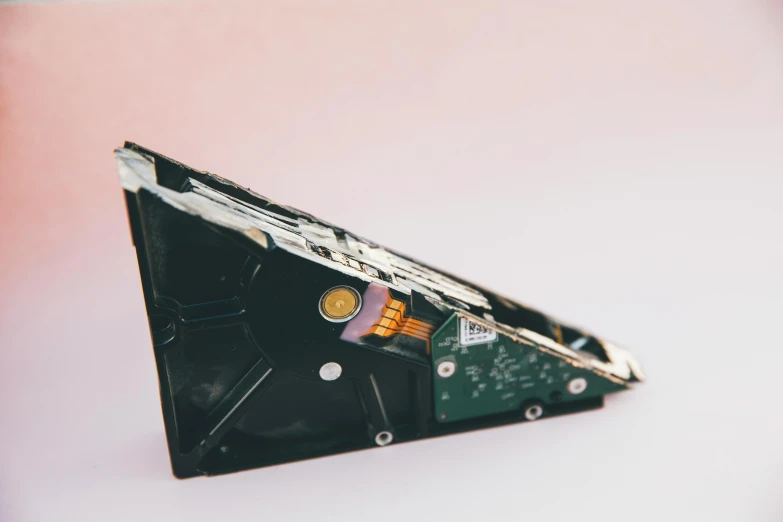 a broken hard drive sitting on top of a table, an abstract sculpture, unsplash, looking from side, triangle, motherboard, back - view