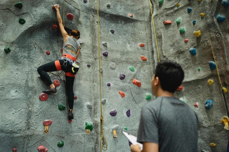 a man climbing up the side of a rock wall, pexels contest winner, interactive art, asian female, male and female, indoor, 15081959 21121991 01012000 4k