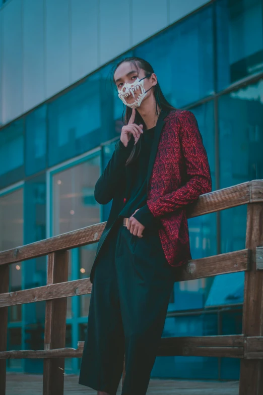 a woman wearing a mask sitting on a bench, a picture, trending on pexels, aestheticism, black and red suit, asian man, at a fashion shoot, androgyny