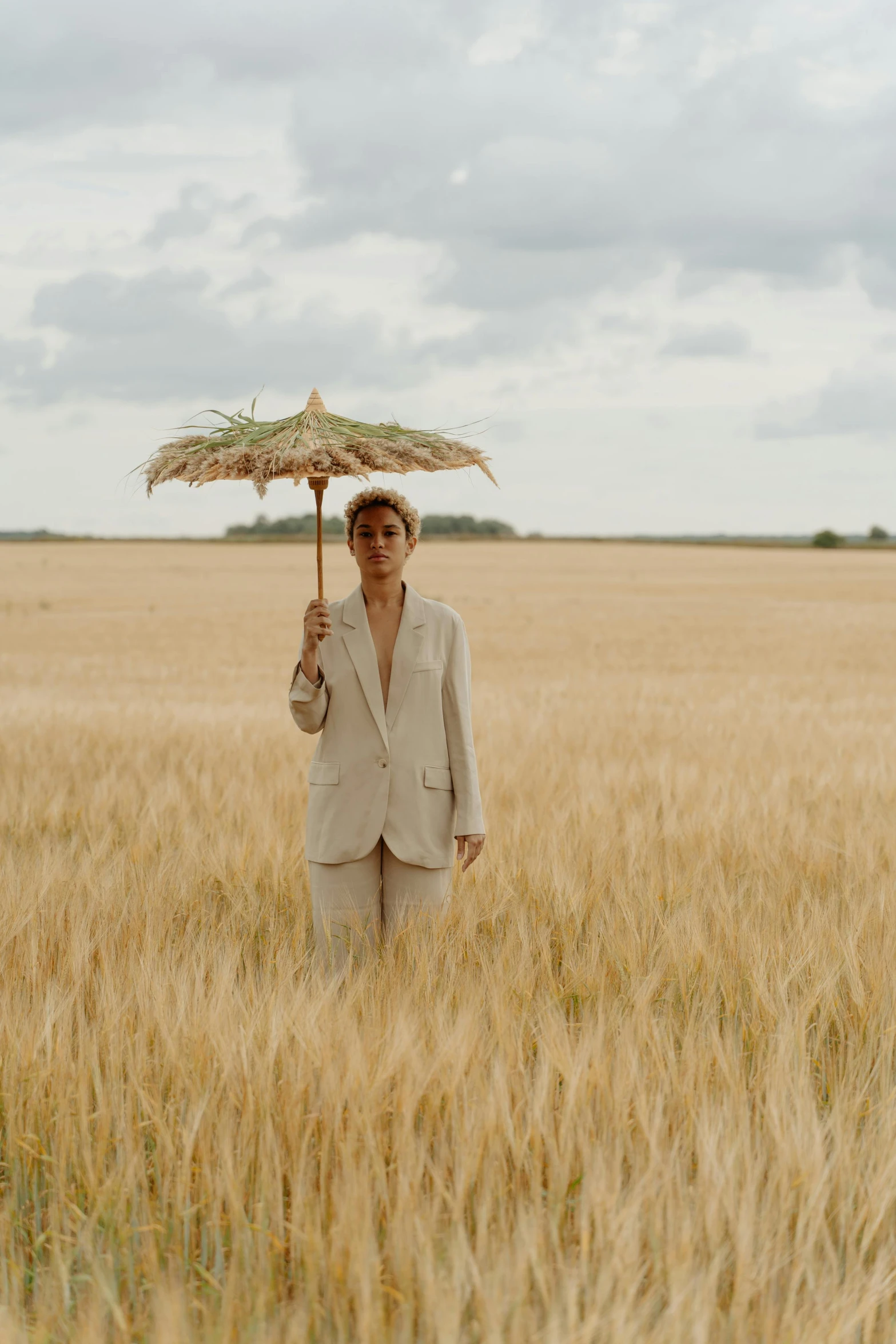 a man standing in a field holding an umbrella, tan suit, ashteroth, filmstill, hammershøi