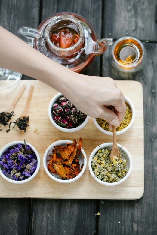 a wooden table topped with bowls filled with different types of tea, process art, holding magic flowers, partially cupping her hands, bay area, candy treatments