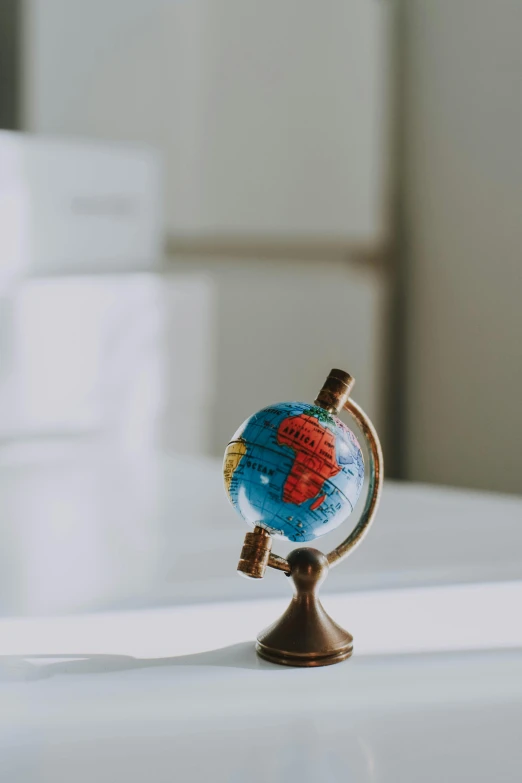 a small globe sitting on top of a white table, detailed product image, zoomed in, sunlit, colour photo