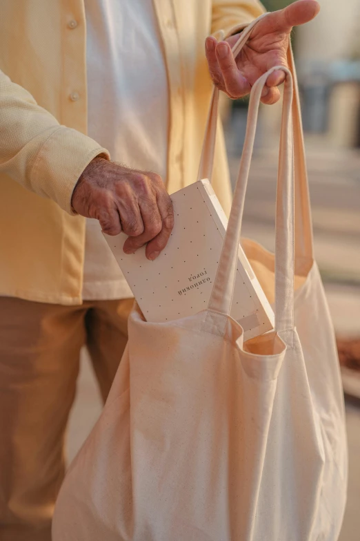 a close up of a person holding a bag, by Jan Tengnagel, happening, holding a book, people shopping, linen, soft glow