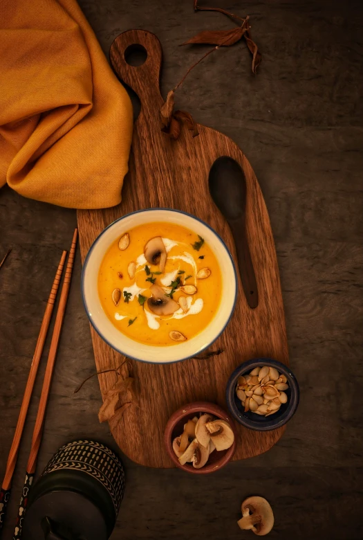 a bowl of soup sitting on top of a wooden cutting board, inspired by Tang Di, shutterstock contest winner, hurufiyya, pumpkin, shot with sony alpha, square, south east asian with long