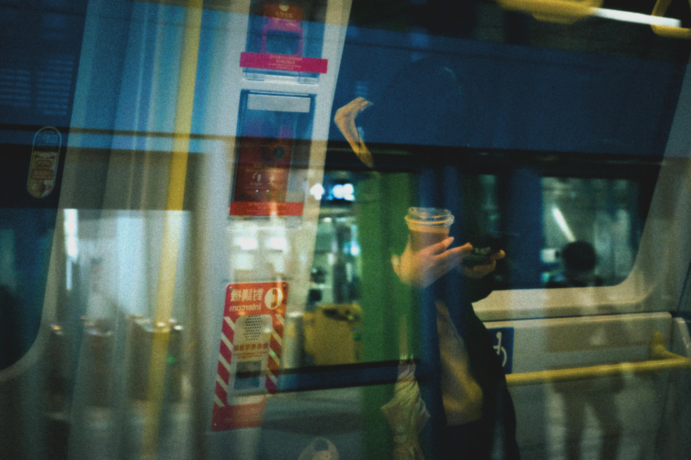 a person holding a cup of coffee on a train, by Nathalie Rattner, neon reflections, bus stop, overexposed photograph, medium format. soft light