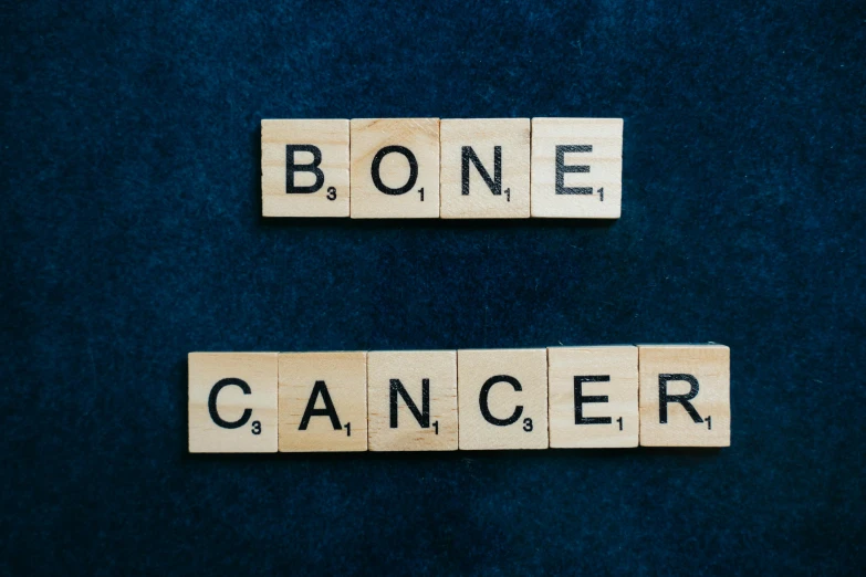 the word bone cancer spelled in scrabbles on a blue background, by Muirhead Bone, on a dark background, lying on bones, background image, no crop