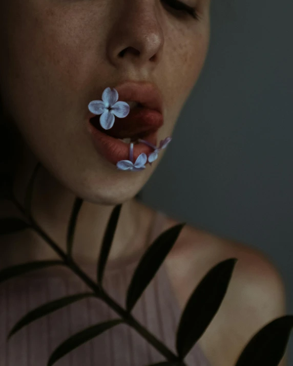 a woman with a flower in her mouth, inspired by Elsa Bleda, trending on pexels, her iridescent membranes, low quality photo