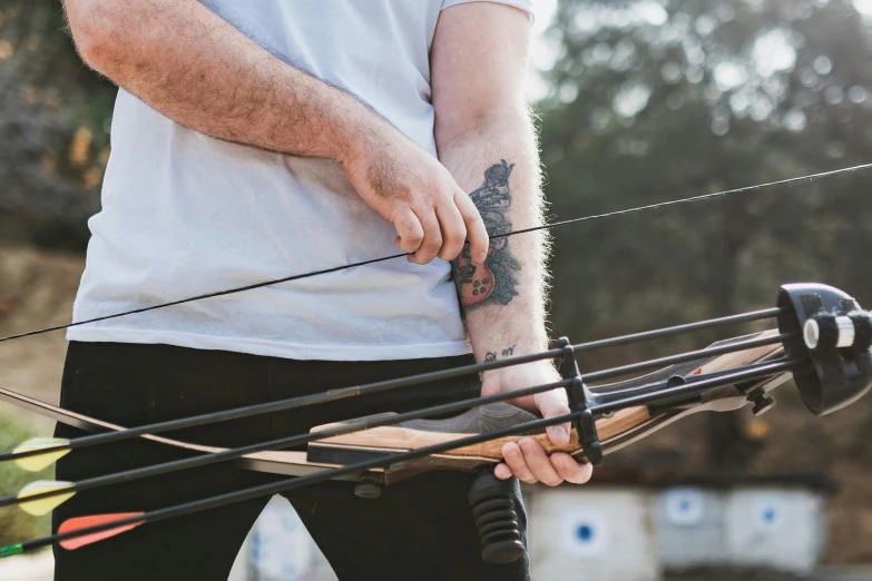 a close up of a person holding a bow and arrow, by Joe Bowler, pexels contest winner, lachlan bailey, closeup of arms, panoramic shot, exterior shot