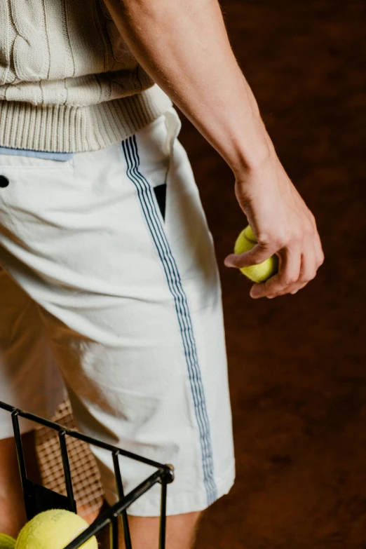 a man holding a basket full of tennis balls, by Jan Tengnagel, dribble, wearing off - white style, detail shot, large pants, with two front pockets