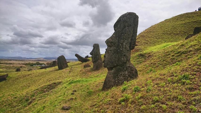 a group of large rocks sitting on top of a lush green hillside, a statue, by Daniel Lieske, pexels contest winner, polynesian god, avatar image, slight overcast weather, an ancient male bearded face