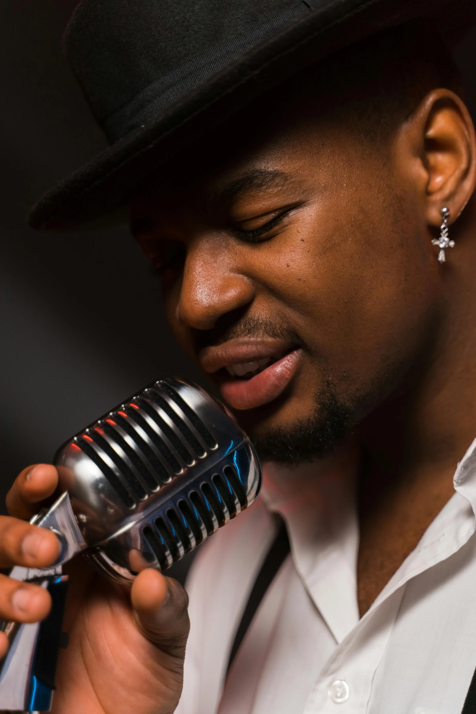 a man in a hat singing into a microphone, inspired by Michael Ray Charles, pexels contest winner, harlem renaissance, close - up studio photo, a handsome, rectangle, split near the left