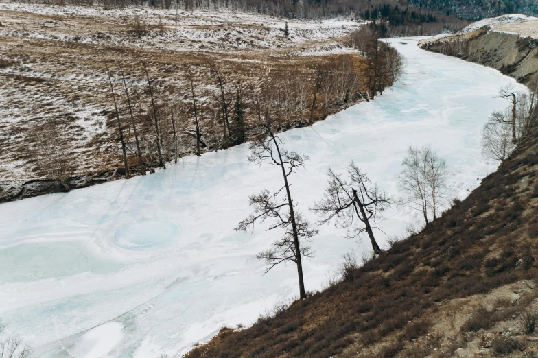 a river running through a snow covered field, by Muggur, pexels contest winner, land art, trees growing on its body, photo of genghis khan, thumbnail, footage