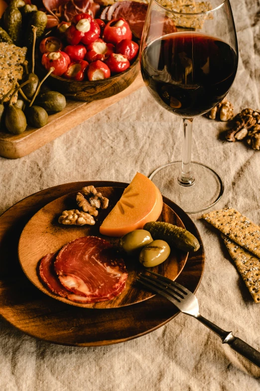 a table topped with a plate of food next to a glass of wine, salami, premium, seasonal, throw