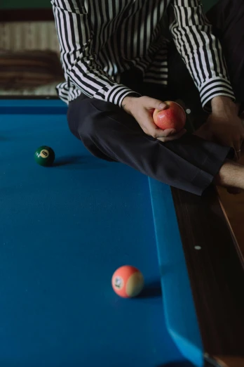 a man sitting on a pool table holding an apple, unsplash, hyperrealism, teal suit, b - roll, bottom shot, rectangle