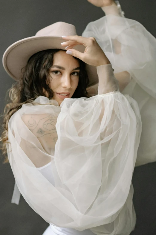 a woman wearing a white dress and a hat, an album cover, inspired by Anita Malfatti, trending on pexels, cream colored blouse, portrait image, yael shelbia, wearing organza gown