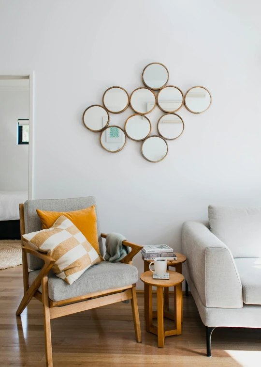 a living room filled with furniture and a wooden floor, inspired by Constantin Hansen, trending on unsplash, round mirror on the wall, white bg, silver and yellow color scheme, manuka