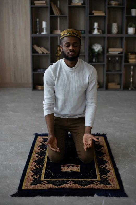 a man sitting on a rug in a room, by Everett Warner, trending on unsplash, praying posture, brown skin man egyptian prince, square, meditating pose