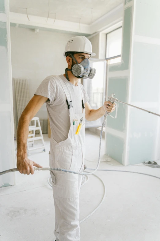 a man that is standing in the middle of a room, an airbrush painting, pexels contest winner, arbeitsrat für kunst, wearing a round helmet, dust mask, white, construction