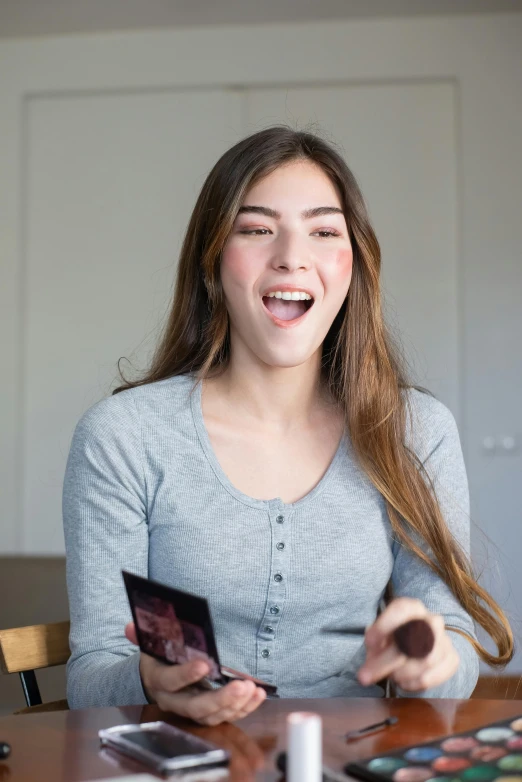 a woman sitting at a table holding a cell phone, pokimane, expressing joy, like a catalog photograph, with mouth open