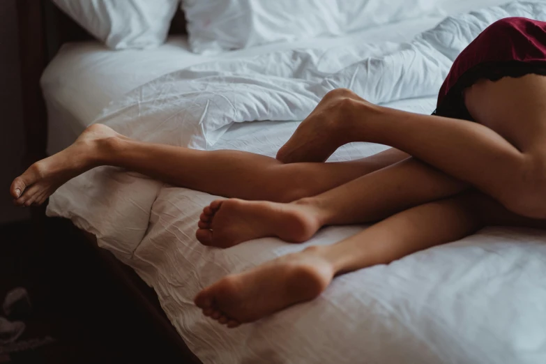 a woman laying on a bed with her legs crossed, trending on pexels, holding each other, male and female, entangled vibrating, very thin