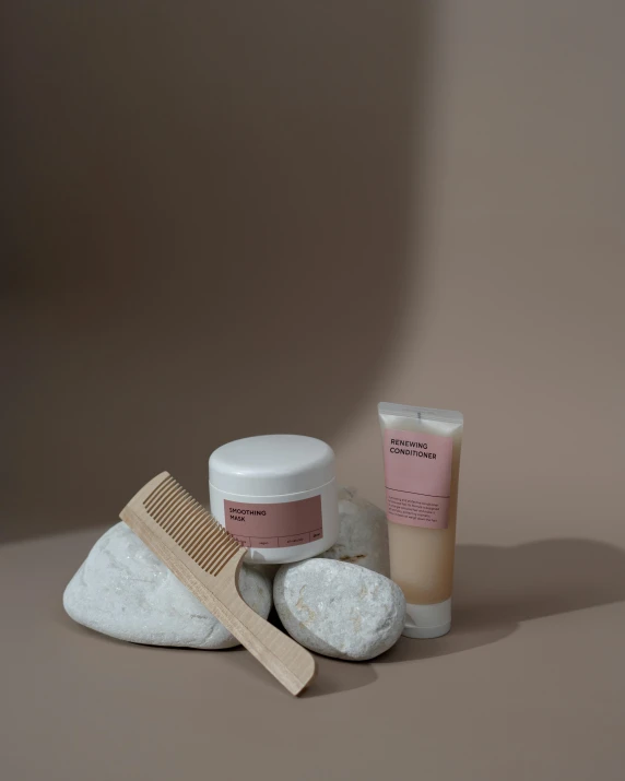a wooden comb sitting on top of a pile of rocks, inspired by Henriette Grindat, unsplash, dau-al-set, minimal pink palette, toothpaste refinery, full view of face and body, formulas