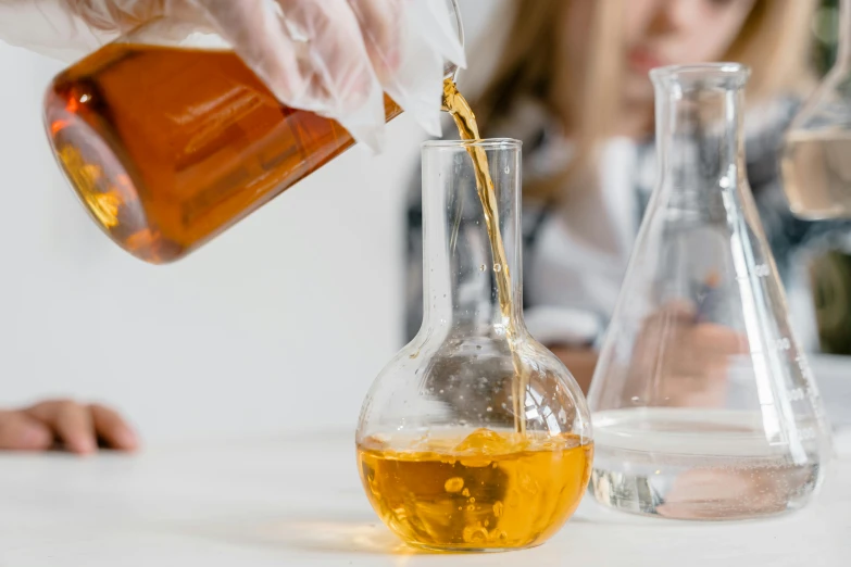 a close up of a person pouring liquid into a glass, pexels contest winner, working in her science lab, manuka, dezeen, mead