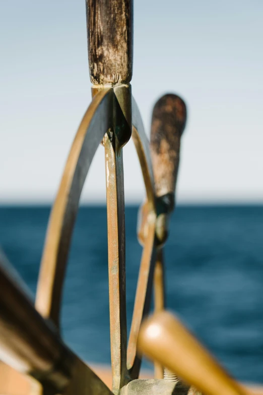 a close up of a steering wheel on a boat, by David Simpson, unsplash, new sculpture, fronds, axes, on ocean, gold