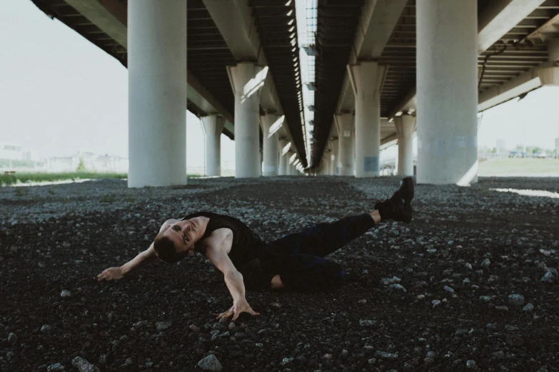 a woman laying on the ground under a bridge, pexels contest winner, man standing in defensive pose, non binary model, recital, cracked