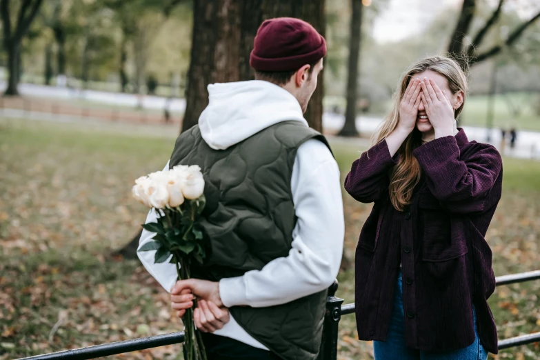 a man standing next to a woman holding a bouquet of flowers, a photo, by Julia Pishtar, pexels contest winner, girl wearing hoodie, man proposing his girlfriend, saying, college