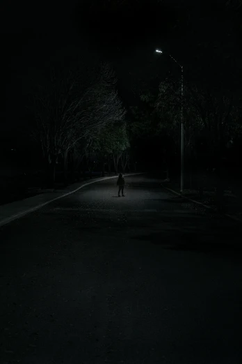 a person standing in the middle of a road at night, an album cover, dark. no text, a park, skinwalker, dark image