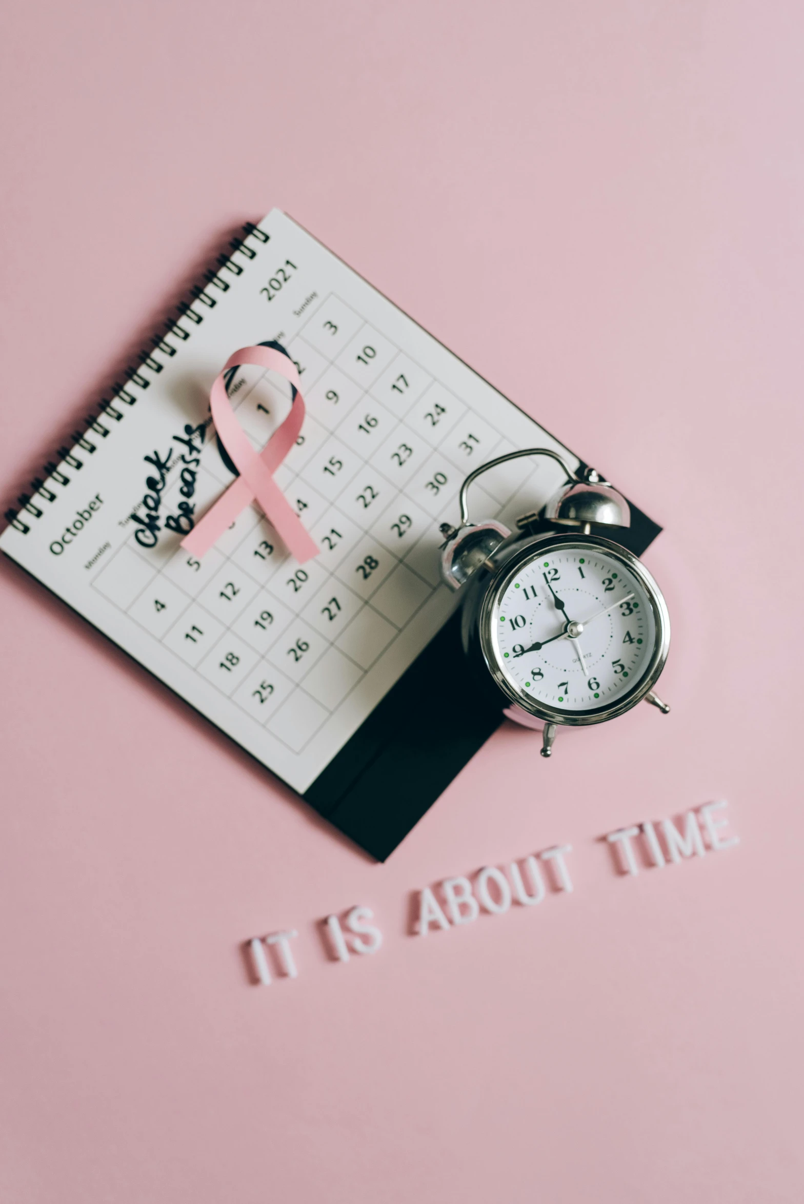 an alarm clock sitting next to a pink ribbon, a picture, thumbnail, flat lay, tumours, day time