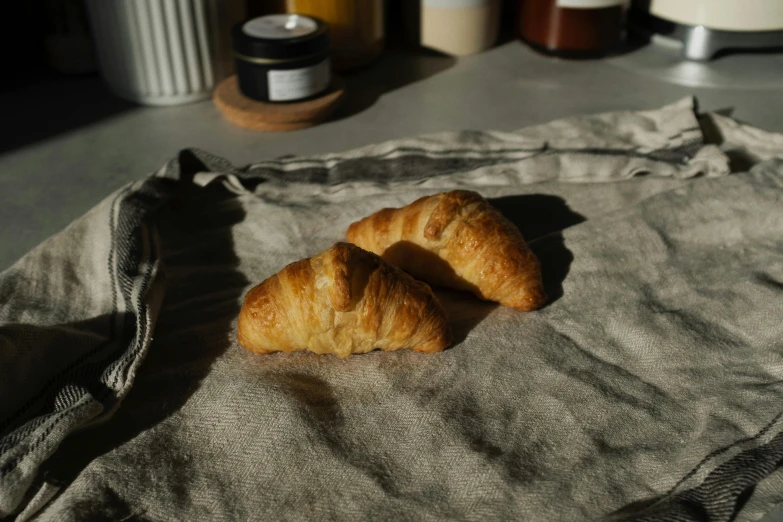 a couple of croissants sitting on top of a cloth, a portrait, unsplash, very sunny, shot on sony a 7, :: morning, linen canvas