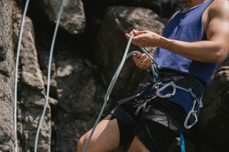 a man that is on a rock with a rope, belaying, body harness, blue, te pae