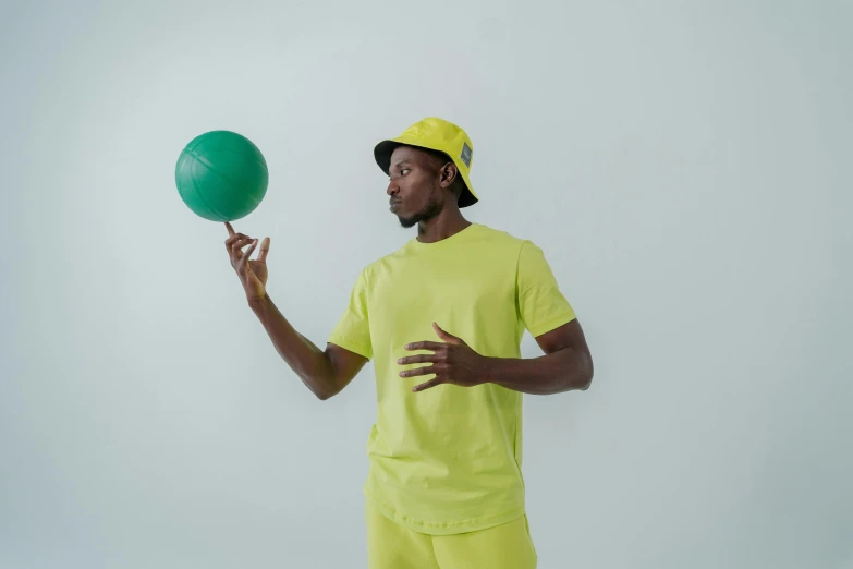 a man in a yellow shirt juggling with a green ball, inspired by Paul Georges, pexels contest winner, off - white collection, ( ( dark skin ) ), green visor, kevin garnett