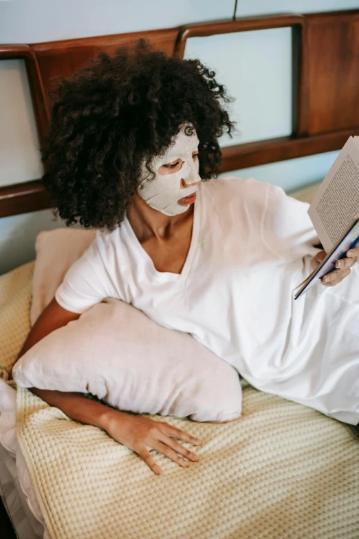 a woman laying in bed reading a book, a cartoon, trending on pexels, happening, african mask, skincare, “ full body, masked face