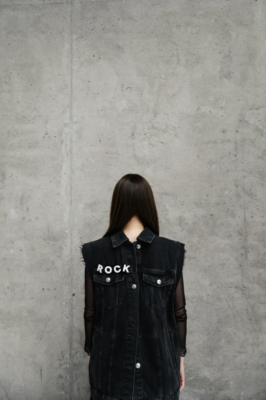 a woman standing in front of a concrete wall, an album cover, pexels contest winner, postminimalism, black vest, ((rocks)), japanese streetwear, rock concert