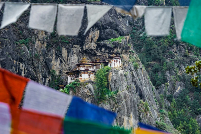 a group of flags hanging from the side of a mountain, inspired by Steve McCurry, pexels contest winner, hurufiyya, bhutan, avatar image, white marble buildings, thumbnail