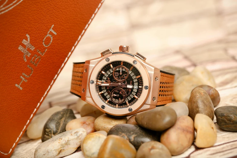 a watch sitting on top of a pile of rocks, hublot, bronze poli, a wooden, thumbnail