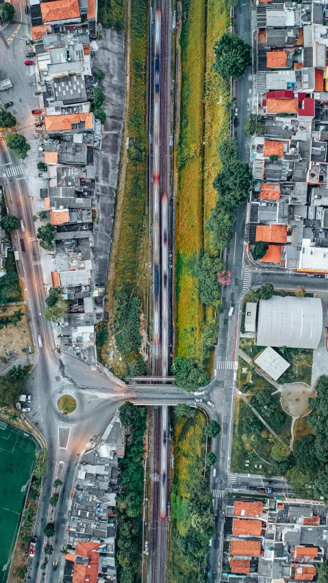 an aerial view of a city with lots of buildings, an album cover, by Alejandro Obregón, pexels contest winner, rail tracks, freeway, brazil, vegetated roofs