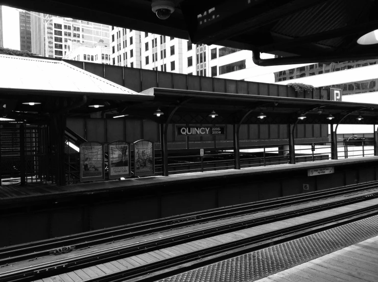 a black and white photo of a train station, a black and white photo, inspired by Vivian Maier, flickr, modern chicago streets, on the qt, from the distance, gurney