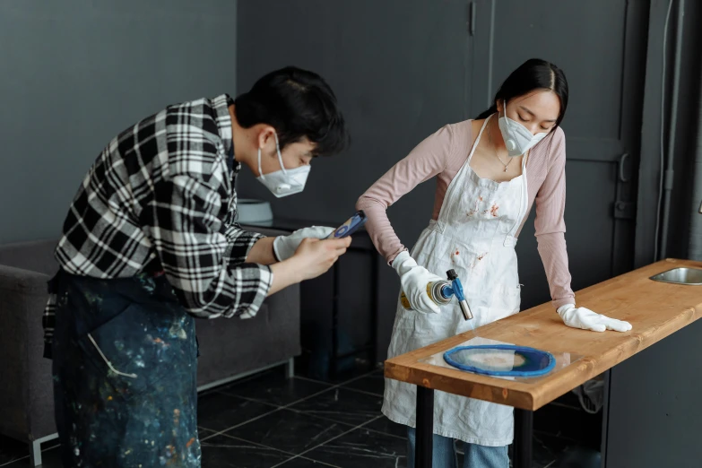 a couple of people that are standing in front of a table, by Jang Seung-eop, pexels contest winner, arbeitsrat für kunst, coating a stubborn core.', wearing facemask, as well as the handyboy, pour paint