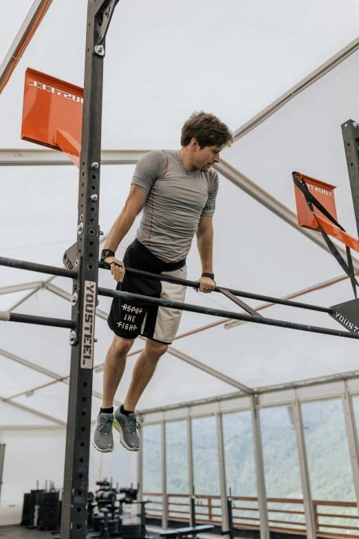 a man on a pull up bar in a gym, by Jan Tengnagel, pexels contest winner, happening, orange grey white, in a race competition, summer weather, ben askren