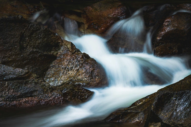 a stream of water flowing between two large rocks, an album cover, unsplash contest winner, australian tonalism, thumbnail, chocolate river, unsplash 4k, multiple stories