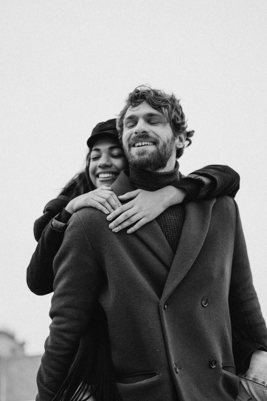 a black and white photo of a man carrying a woman, happy people, with a beard and a black jacket, 30-year-old french woman, ssense