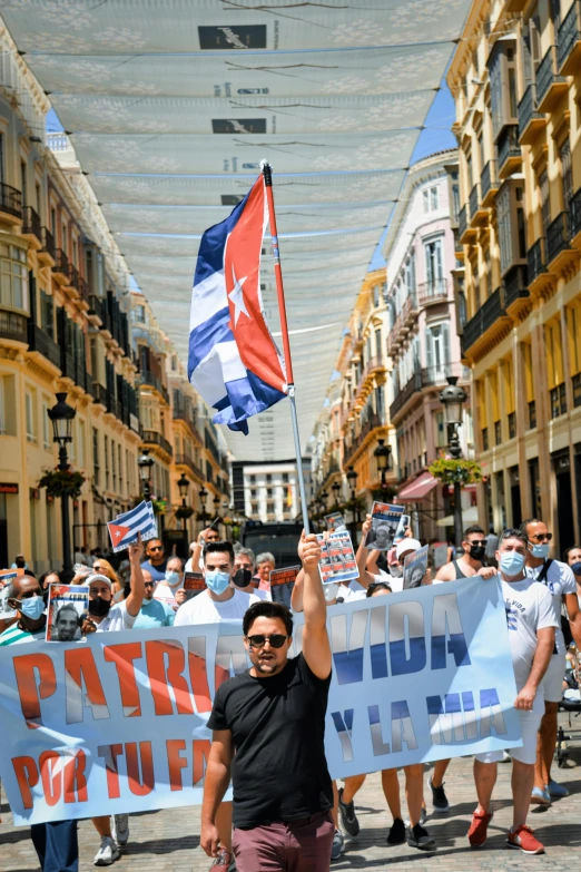a group of people walking down a street holding flags, verdadism, wearing facemask and sunglasses, pedro correa, thumbnail, ( ( theatrical ) )